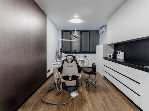 Treatment room at ESTHEMAX: the dental chair at the far end, below the window, and white cabinets along the wall