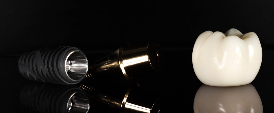 A dental implant, its abutment and a crown, side by side